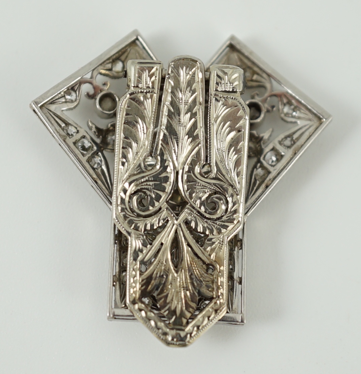 A Belle Epoque pierced white gold and millegrain set diamond cluster set clip brooch